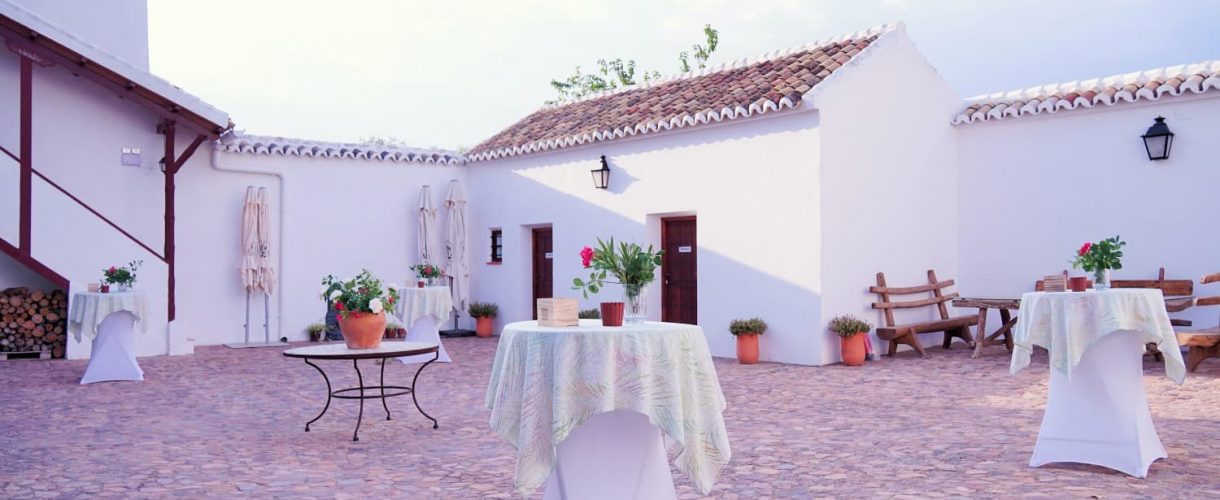 Patio andaluz preparado para evento con mesas altas